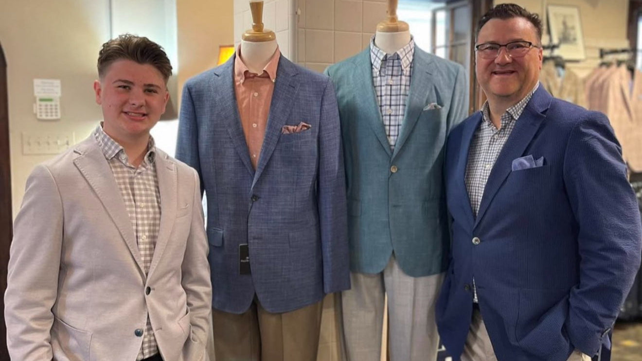 Two men posing with suits on mannequins in a store setting