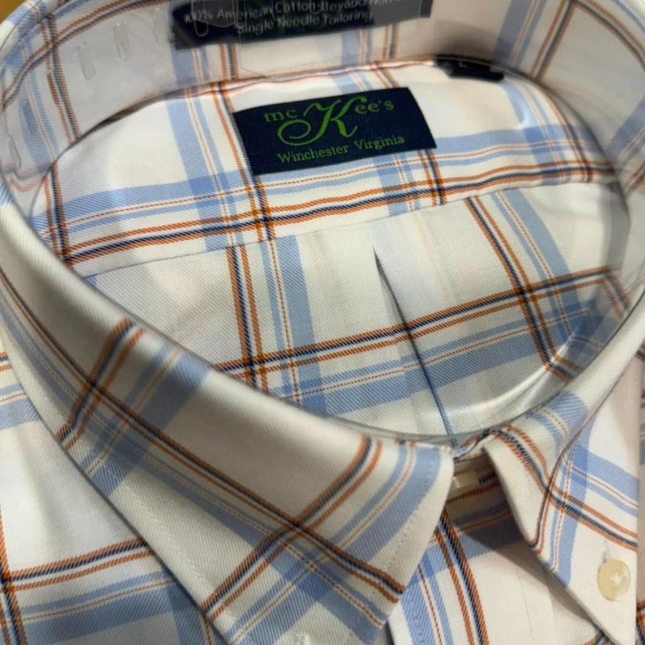 Close-up of a plaid shirt collar with a brand label on a wooden surface