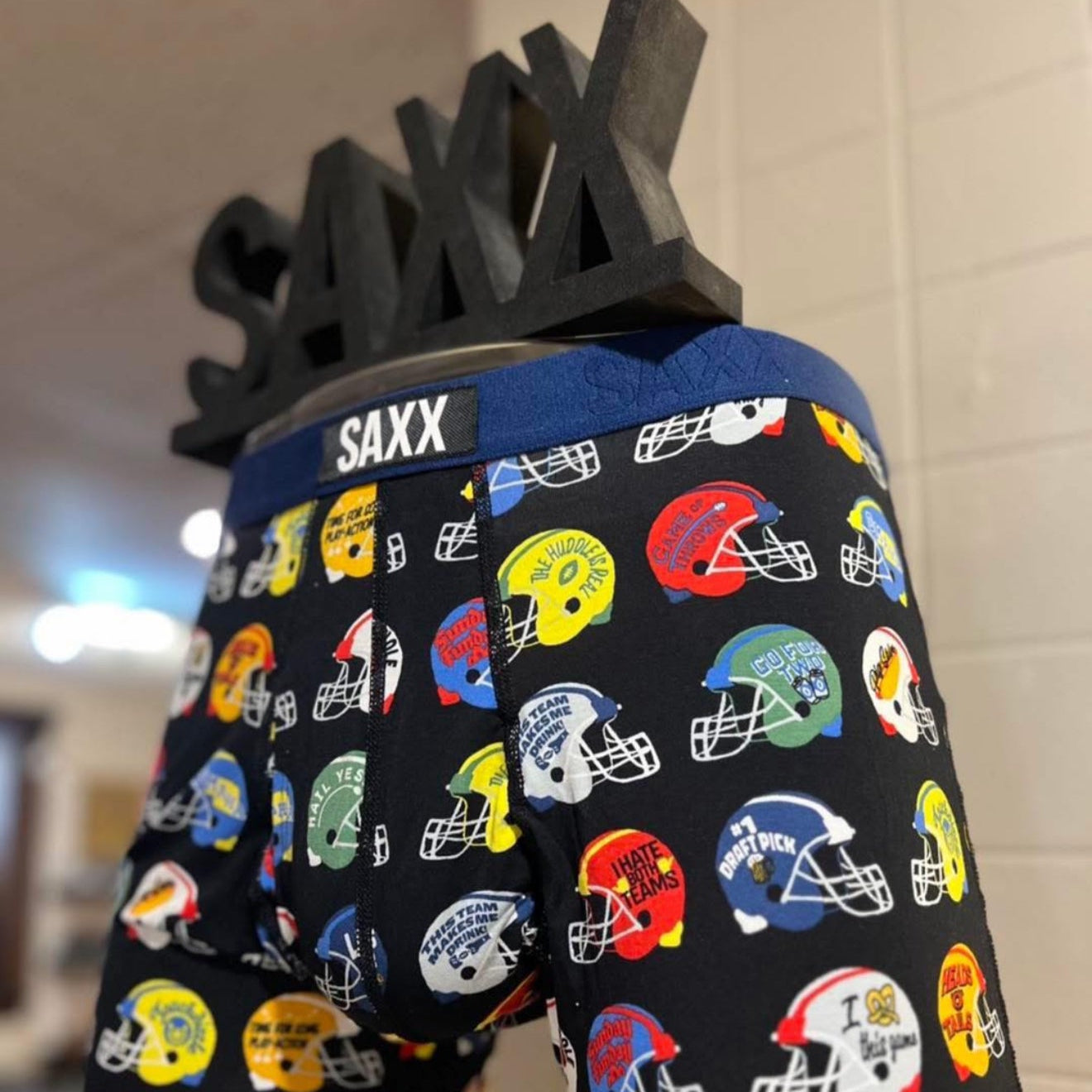 Colorful helmet-patterned boxer briefs with SAXX branding on a mannequin.