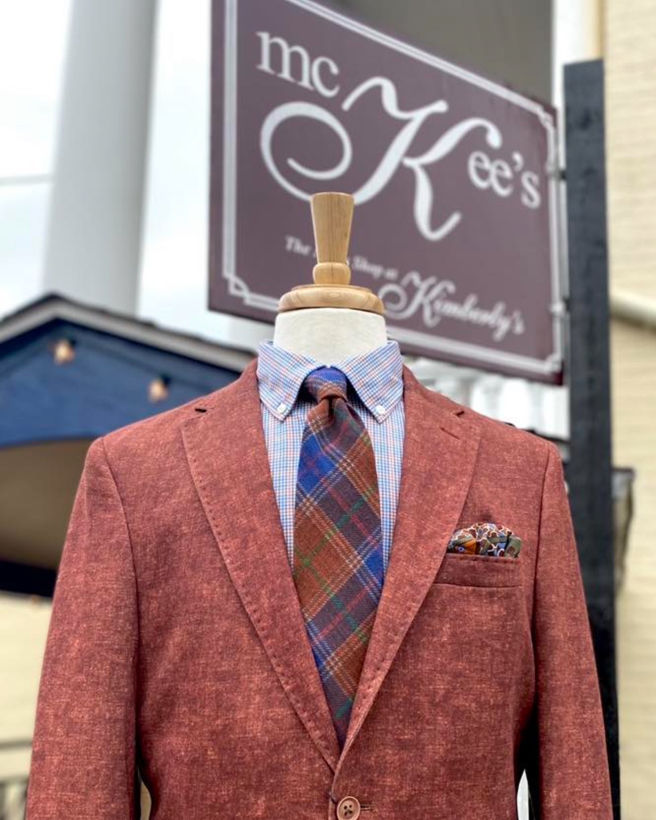 Mannequin wearing a red blazer with a plaid tie and shirt, in front of the McKee's Mens Store sign in Winchester VA.