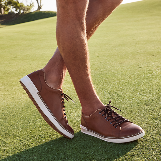 Person wearing brown leather golf shoes on a golf course